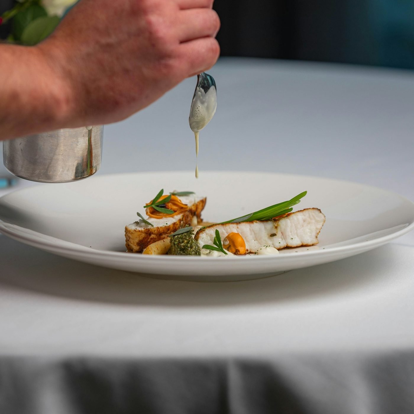A plated fine-dining dish of fish and vegetables