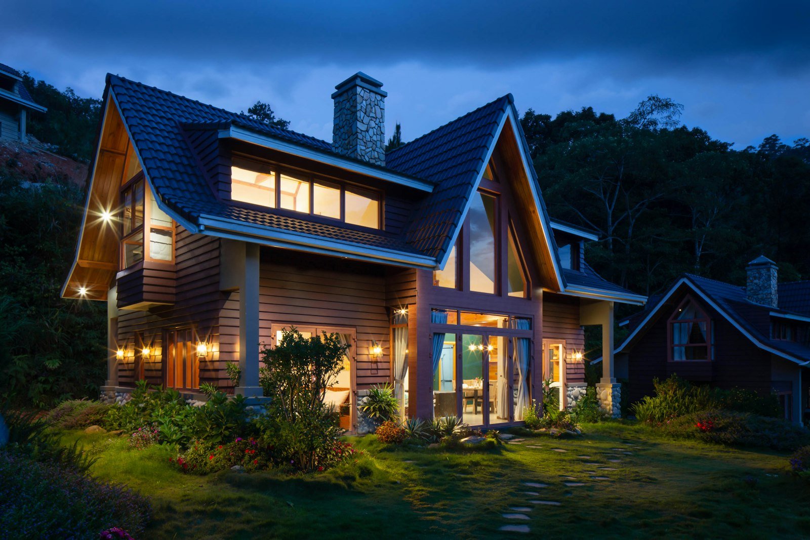 Lit residential home at dusk with a landscaped garden and stone path to the entrance